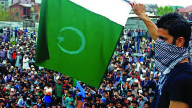 A masked man waves Pakistan flag at a rally to welcome All India Hurriyat Conference leader Syed Ali Shah Geelani on his arrival in Srinagar from Delhi. - Photo courtesy PTI