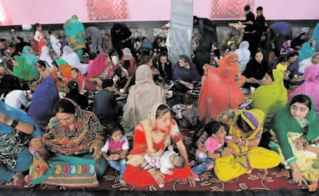 Hindu and Sikh families wait for lunch inside a Gurudwara in Kabul