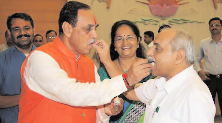 Gujarat Chief Minister Vijay Rupani and Deputy Chief Minister Nitin Patel share sweets at CMO before taking charge as the Gujarat Chief Minister at Gandhinagar on Monday. - Image - PTI