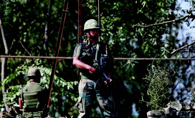 Indian Army soldiers keep guard on top of a shop along a highway on the outskirts of Srinagar on September 29. (Reuters)