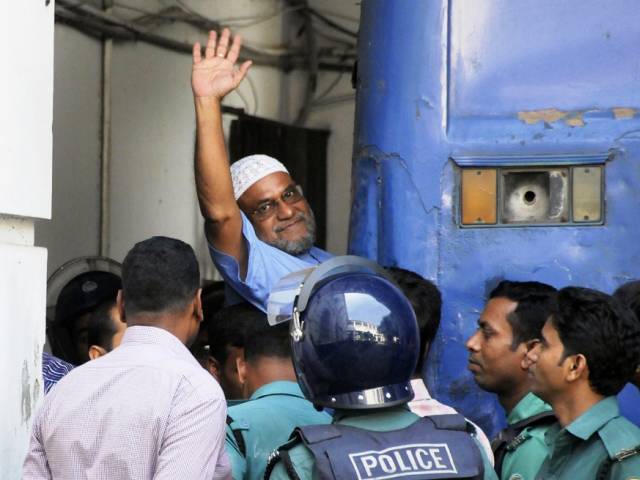Jamaat-e-Islami party leader, Mir Quasem Ali waves his hand as he enters a van at the International Crimes Tribunal court in Dhaka on November 2, 2014. PHOTO: AFP
