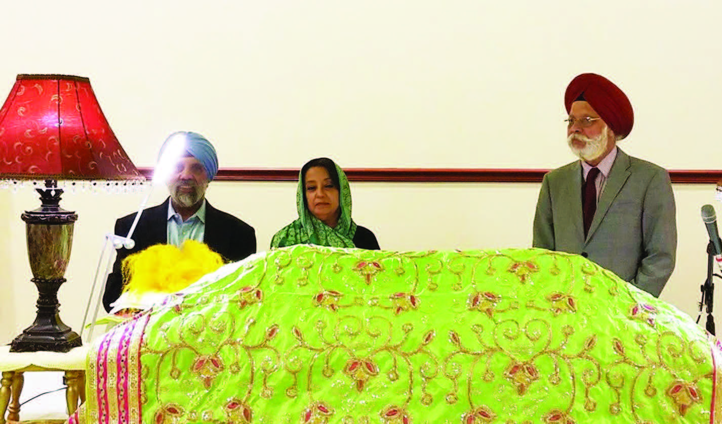 Consul General of India in New York, Riva Ganguly Das, flanked by gurdwara representatives, stands behind Guru Granth Sahib at a Gurdwara in Connecticut