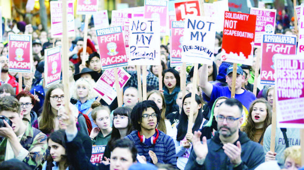 Protesters hold signs during a protest the election of President-elect Donald Trump in downtown Seattle on November 9, 2016